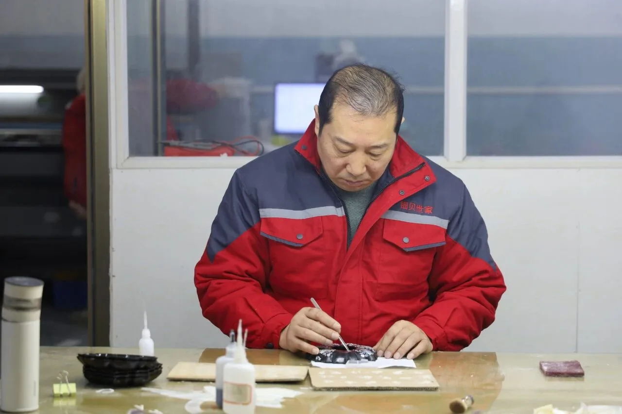 Ji Zhengqiang working on a luodian piece in the workshop